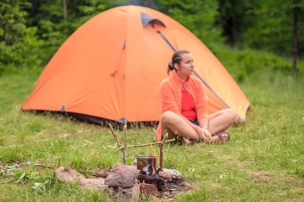 Девушка-туристка сидит возле палатки — стоковое фото