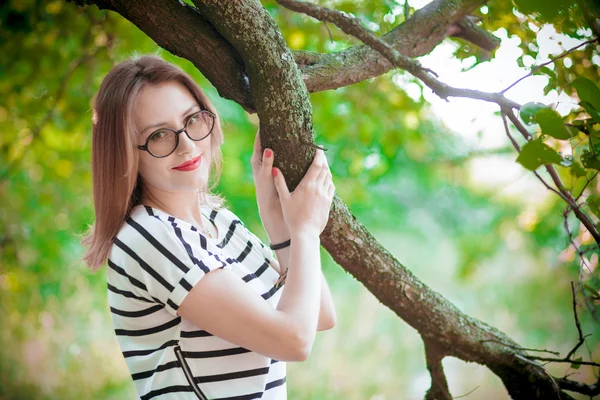 La muchacha en las copas cerca del árbol — Foto de Stock