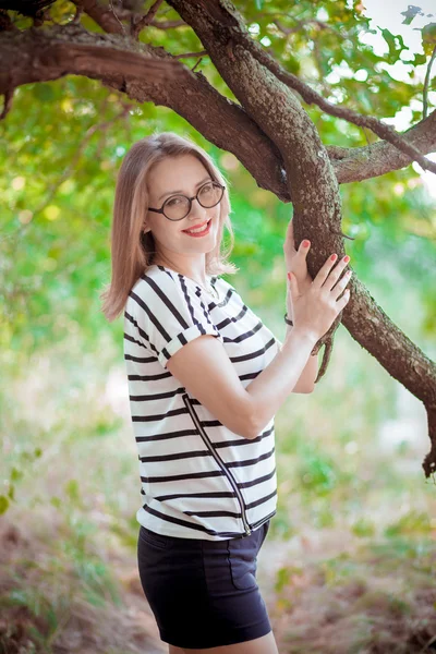 Het meisje in glazen in de buurt van een boom — Stockfoto