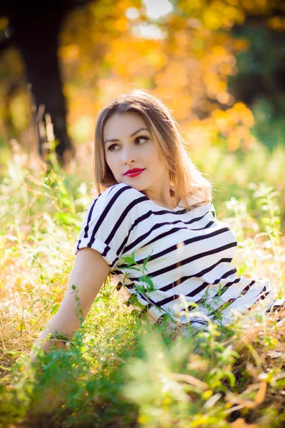 Sarı çim üzerinde oturan kadın — Stok fotoğraf
