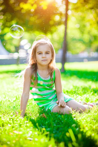Little girl sitting on the grass — Stock Photo, Image