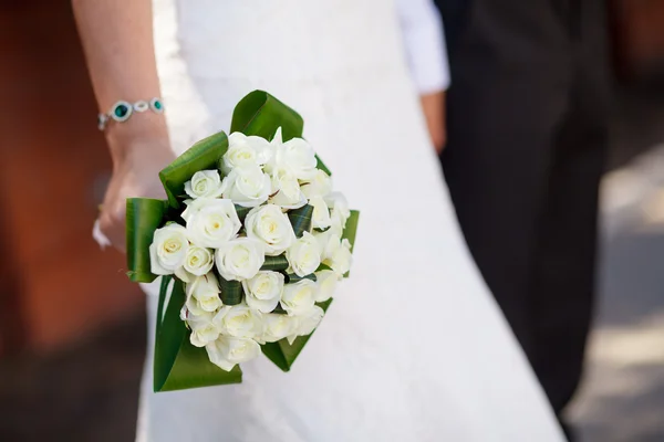 Bouquet da sposa nelle mani di rose bianche e foglie verdi — Foto Stock