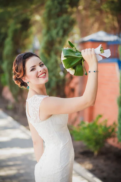 Buquê de noiva nas mãos de rosas brancas e folhas verdes — Fotografia de Stock