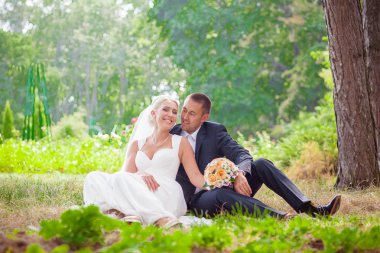 Gelin ve damat çim parkta oturmak
