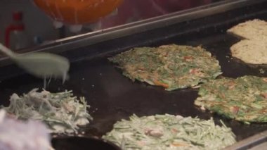 Gukje Uluslararası Pazarı Busan şehrinde Bindae-tteok. Bindaetteok, kızarmış buchimgae, fasulyeli lezzetli gözleme, sebze, et. Güney Kore 'de sokakta yiyecek satan Koreli satıcılar.