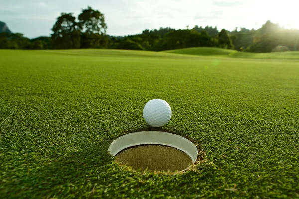 Les lumières de fusée photo de balle de golf blanche près du trou sur fairway w — Photo