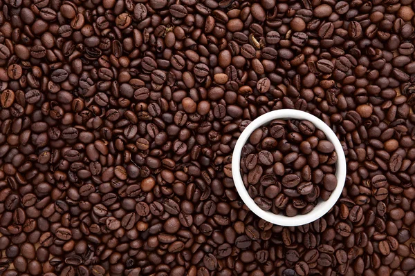Белая чашка жареного кофейного зерна поверх плоского слоя коричневой роа — стоковое фото
