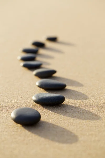 Set of hot stone on white sand calm beach in backbone shape. sel — Stock Photo, Image