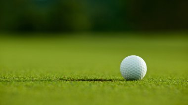 seçici odak. yeşil çim iyi f üzerinde delik yakınındaki beyaz golf topu