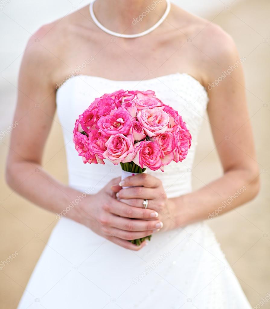 Young bride holding pink rose wedding bouquet