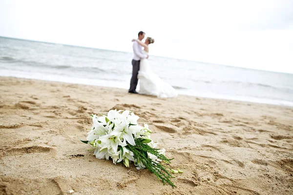 Floare buchet de nunta aglomerat cu cuplu pe plaja — Fotografie, imagine de stoc