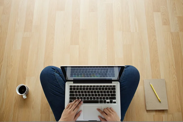 Mladá žena pomocí přenosného počítače na dřevěnou podlahu — Stock fotografie