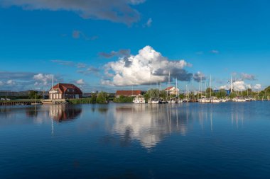 Harlesiel 'deki Harle nehrinde yelkenli ve yatlarla manzara. Harlesiel, Almanya 'nın Kuzey Denizi kıyısında yer alan Doğu Frizya' da bir tatil beldesidir..