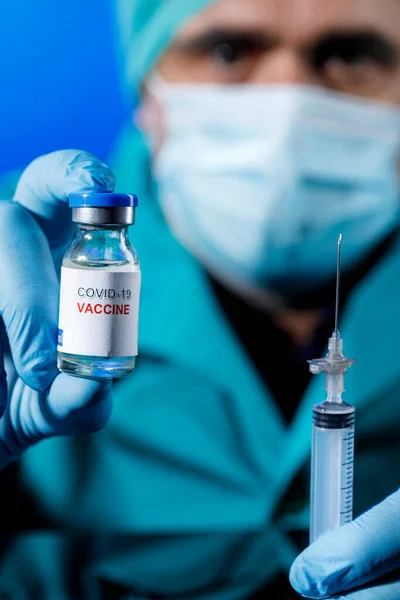 一个医生拿着蓝色疫苗和注射器的特写镜头 — 图库照片