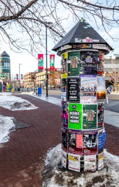 Calgary, Alberta, Kanada, 1 Şubat 2021: Morris sütunu veya Litfass sütunu olarak da bilinen silindirik reklam panosu, Kensington, Calgary 'deki etkinlikler için eski ve renkli reklam ve posterleri ve diğer mesajları içeriyor.