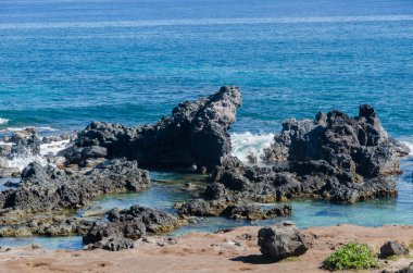 Pasifik mavi okyanusu ve unutulmuş bir kumsalda kayalık bir bölge.