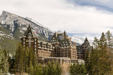 Banff Ulusal Parkı 'ndaki ünlü tarihi otelin arka planında birkaç kayalık tepe var.