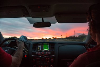 Arizona 'da gün batımında araba kullanmak. Kiralık arabanın arkasından bir görüntü var. Bu Nissan Donanması bizi tüm yürüyüş yerlerimize götürdü ve bu gün batımı gibi harika manzaralar bulmamıza yardım etti..