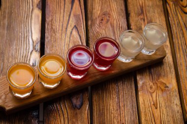 Böğürtlenler ve ahşap bir arka planda meyveler üzerinde renkli alkollü tentürler.