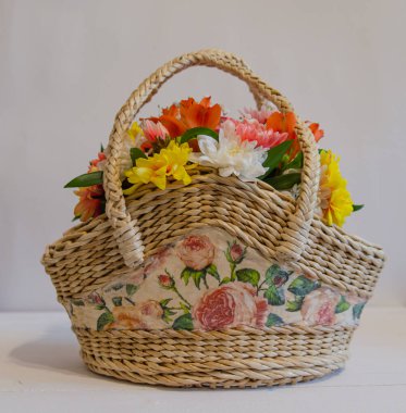 Açık renkli arka planda çiçekli hasır sepet. Tatiller ve selamlar