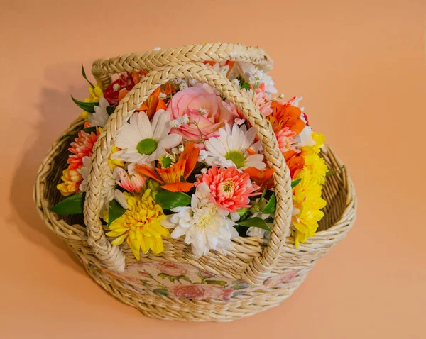 Wicker basket with flowers on a light colored background. Holidays and greetings