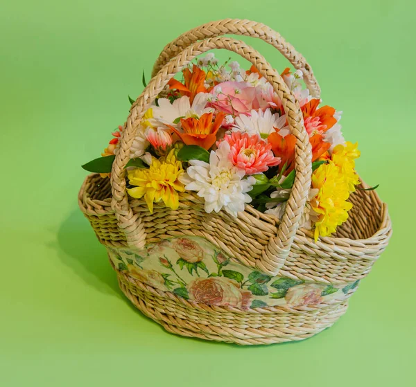 Wicker basket with flowers on a light colored background. Holidays and greetings