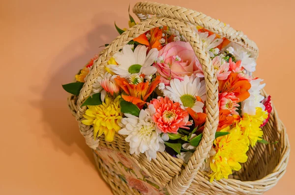 Wicker basket with flowers on a light colored background. Holidays and greetings