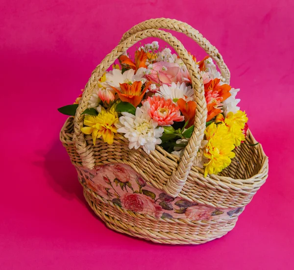 Wicker basket with flowers on a light colored background. Holidays and greetings