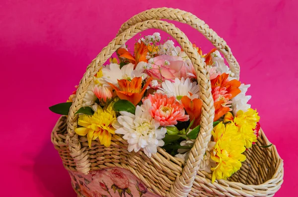 Wicker basket with flowers on a light colored background. Holidays and greetings