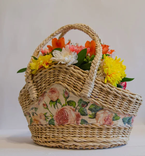 Wicker basket with flowers on a light colored background. Holidays and greetings