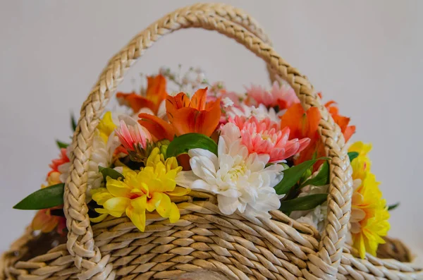 Wicker basket with flowers on a light colored background. Holidays and greetings