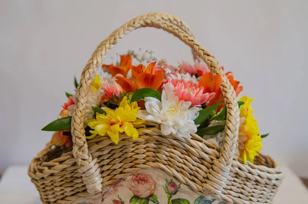 Wicker basket with flowers on a light colored background. Holidays and greetings