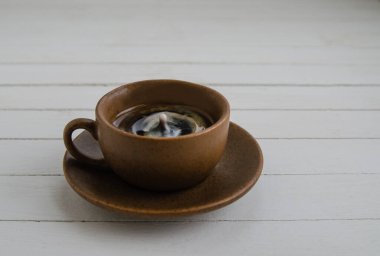 Kahverengi fincanda damla olan sade kahve ve beyaz arka planda fincan tabağı.