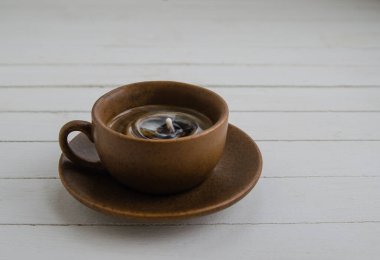 Kahverengi fincanda damla olan sade kahve ve beyaz arka planda fincan tabağı.