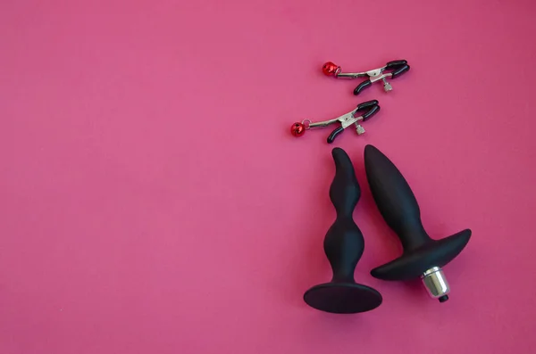性的玩具 粉红背景下的乳头夹和肛门扩张物 图库图片