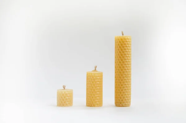Yellow wax candles with a honeycomb pattern on a white background. Interior and esoteric accessories