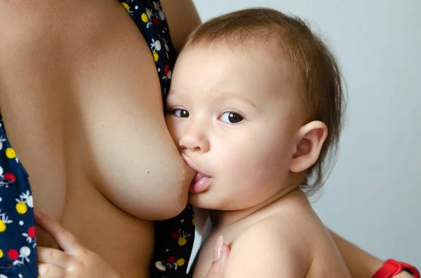 一位年轻的白人母亲正在给她的孩子喂奶 在特写镜头 婴儿的母乳喂养 图库图片
