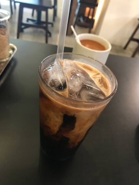 Tayland usulü sütlü kahve. Siyah bir masada sütlü çay geçmişi var.