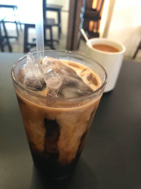 Tayland usulü sütlü kahve. Siyah bir masada sütlü çay geçmişi var.