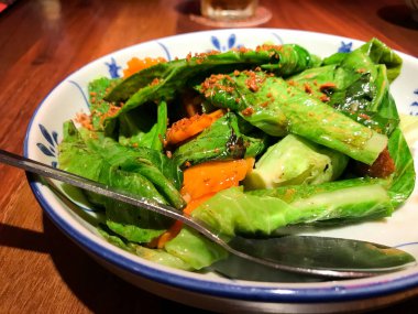 Asya yemeği, kızarmış kailan, havuç ve deniz kulağı soslu domuz rostosu. Tayland restoranında servis yap. Kızarmış sarımsak serpin..