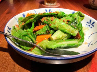 Asya yemeği, kızarmış kailan, havuç ve deniz kulağı soslu domuz rostosu. Tayland restoranında servis yap. Kızarmış sarımsak serpin..