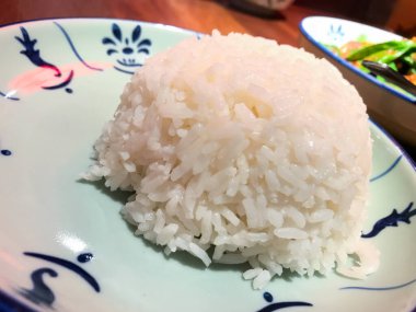 Doğulu bir tabakta sade beyaz pirinç. Tabaklarla birlikte büyük bir kase pirinç servis edilir. Asya yemekleri.