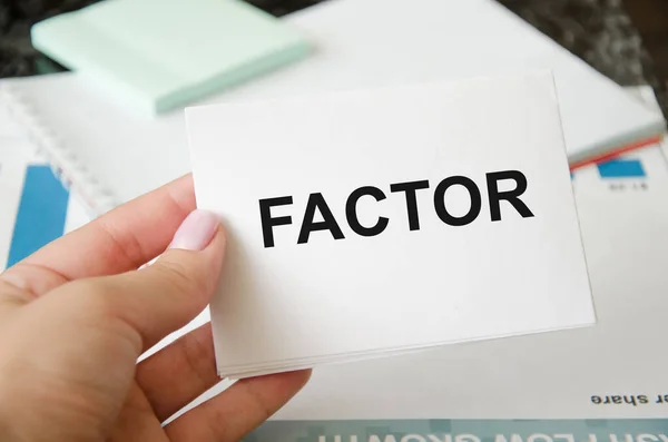 the text factor is written on a white card held by a person. risk factor for business loss, illness. High quality photo