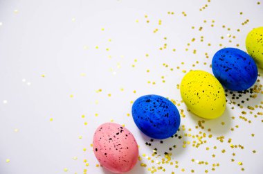 Beyaz arka planda parıltılarla kaplı çok renkli yumurtalar. Paskalya tatili konsepti