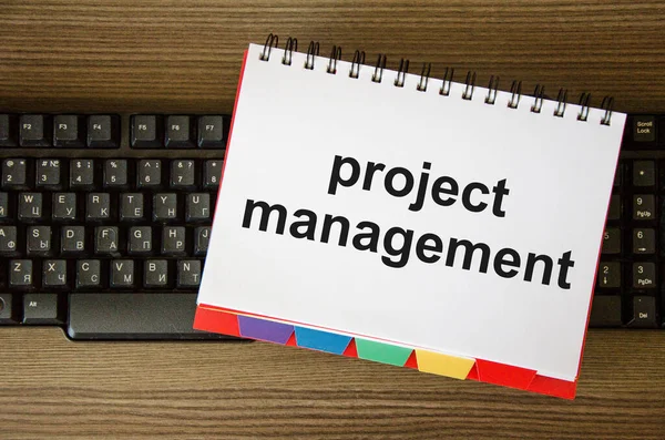 Proje yönetimi programı güncellemesi ya da bilgisayar ve iş programları. Proje Yönetimi kelimesi bir deftere yazılmıştır. Yüksek kalite fotoğraf