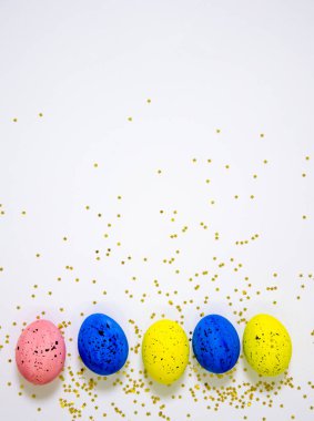 Beyaz arka planda parıltılarla kaplı çok renkli yumurtalar. Paskalya tatili konsepti.