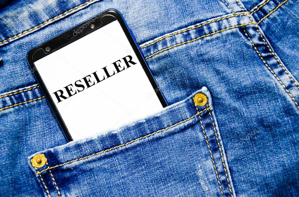 reseller the word is written on the white screen of the phone shortly lies in jeans. text