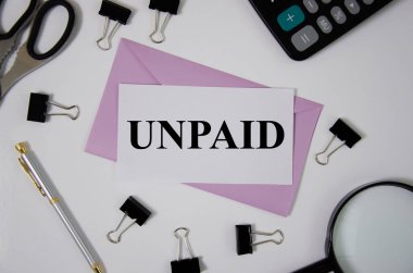 Ofis malzemelerinin yanındaki pembe zarfın üzerine ödenmemiş bir kelime.