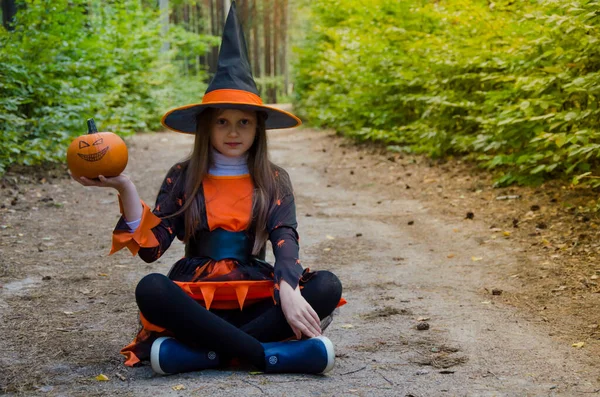 Little Witch Sits Ground Holds Pumpkin One Hand Halloween Holiday — Stockfoto