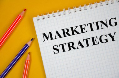 Beyaz kağıt ve pembe arka plana yazılmış pazarlama stratejisi kelimesi